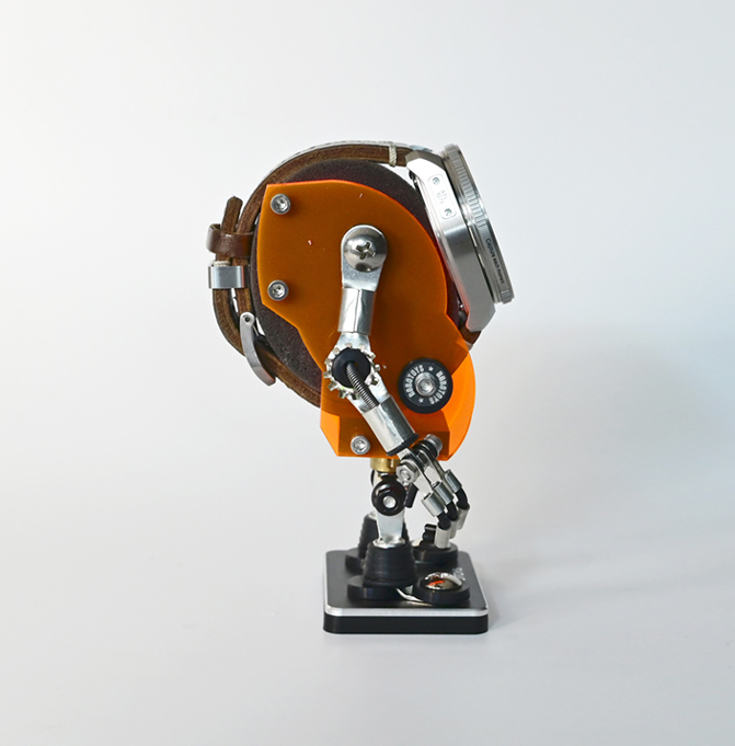 Orange and black minibot watch stand with articulated arms and mechanical details on display base