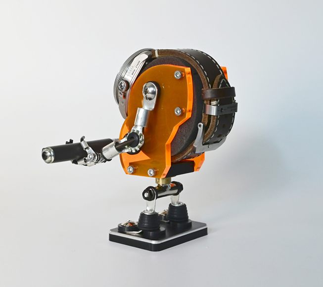 Orange and black mechanical watch stand with chrome lever arm and mounting base, robotic design