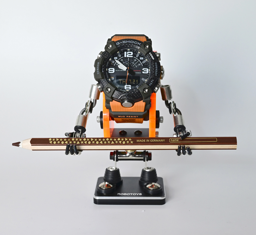 RoboToys Minibot watch stand in neon orange holding G-Shock watch with ski accessory, articulated robot figure display
