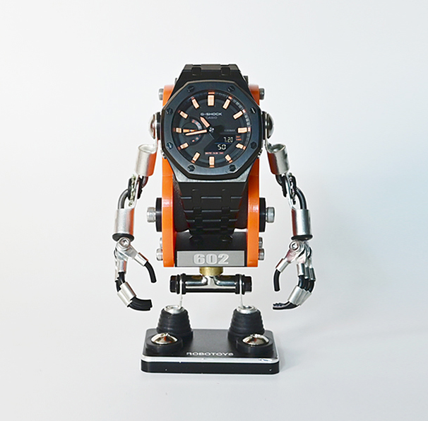 Minibot robot watch stand in orange and silver with articulated arms holding black sports watch