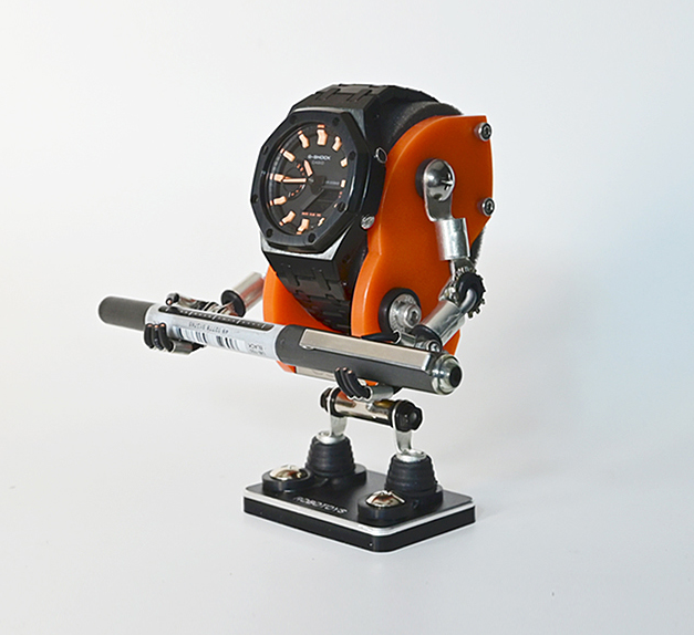 Orange Minibot robotic watch stand holding black digital watch with articulated metal arms and suction cup base