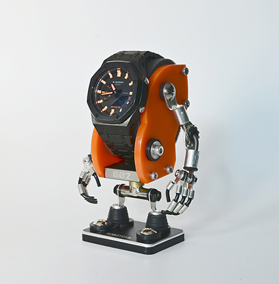 Orange Minibot robotic watch stand with articulated metal arms and hands holding black dial watch, displayed on black base