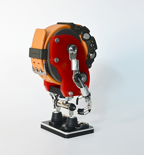 Red and orange minibot watch stand with mechanical details and black base on white background