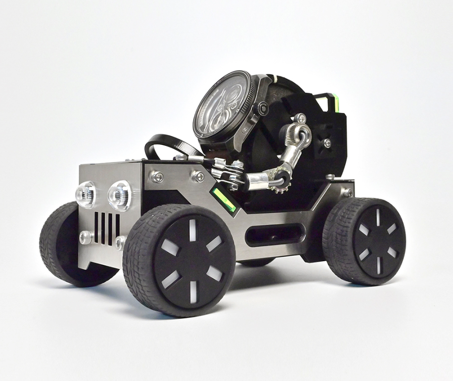 RoboToys Offroader watch stand with metal chassis, LED headlight, black rubber tires, and articulated mechanical arm