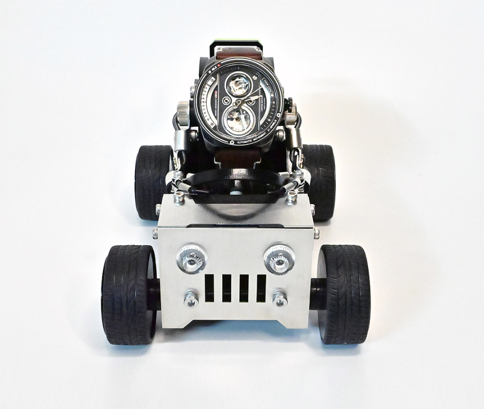 Luxury skeleton watch mounted on white miniature off-road vehicle with black grille and rubber tires, front view
