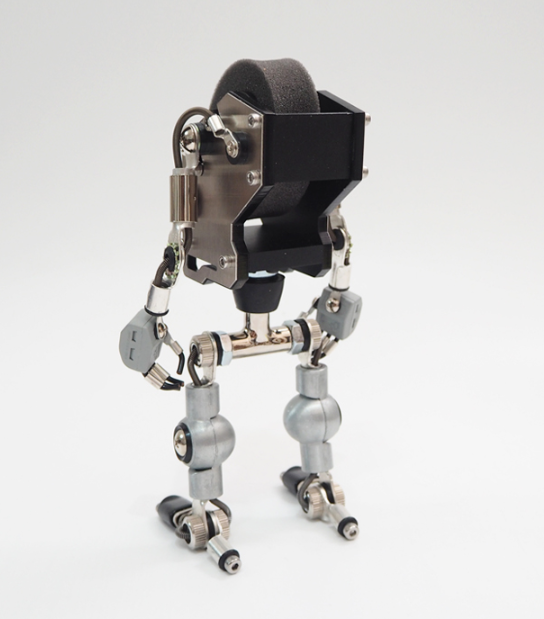 Robotic watch stand holder with silver metal body and articulated mechanical arms and legs, featuring black display platform