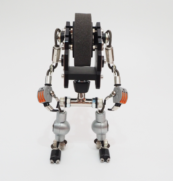 Mechanical robot watch stand in silver and black with articulated arms and legs, featuring orange and black accents, displayed from front view