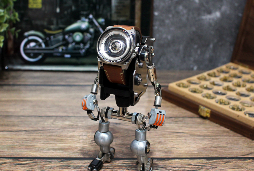 Steampunk robot watch stand in silver metal with brown leather strap holder, displaying mechanical timepiece on wooden surface