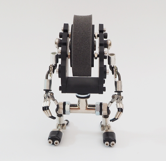 MiniMech black robot watch stand with articulated arms and legs, displaying watch on textured gray band