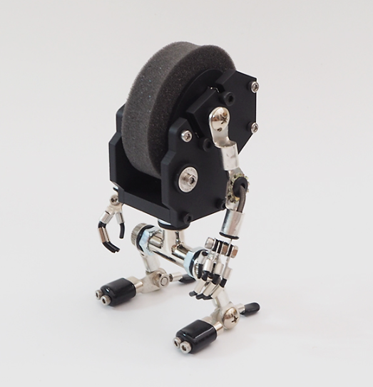 Black MiniMech robot watch stand with articulated metal limbs and grey fabric head detail