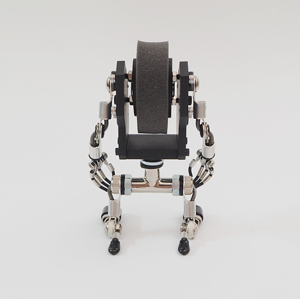 Black MiniMech robot watch stand with articulated mechanical arms and legs, overhead view on white background