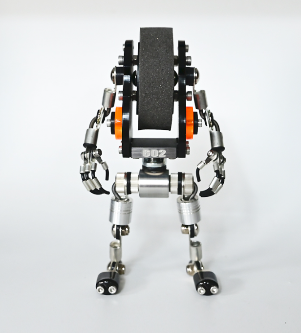 RoboMech robot watch stand with articulated silver metal arms, orange accents, and black grip platform holding timepiece upright