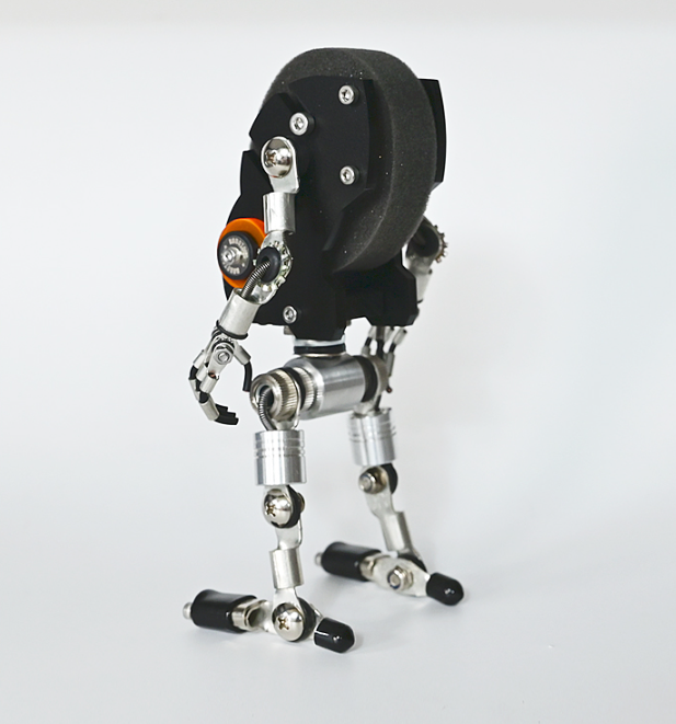 RoboMech black robotic watch stand with articulated metal limbs and orange accents holding timepiece