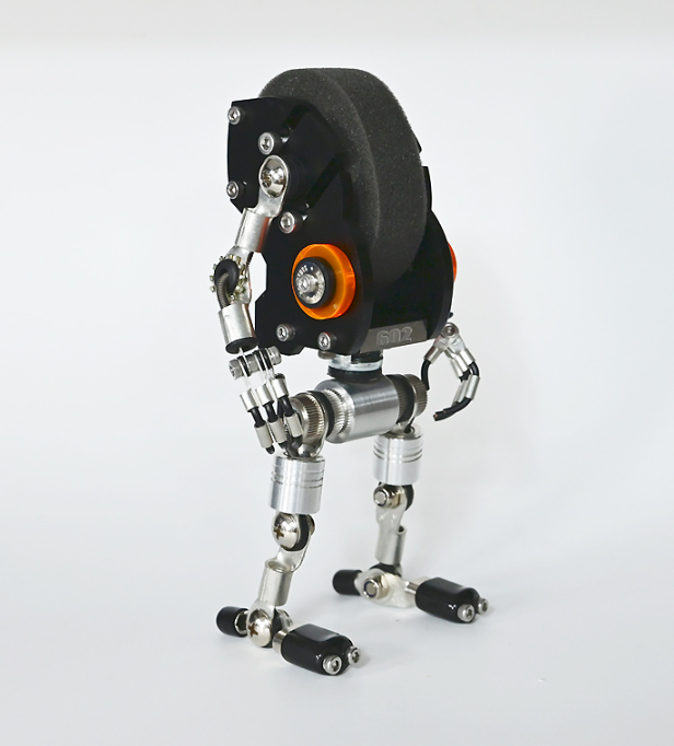 RoboMech black robot watch stand with articulated metal limbs, orange accent wheel, and padded head display, front view
