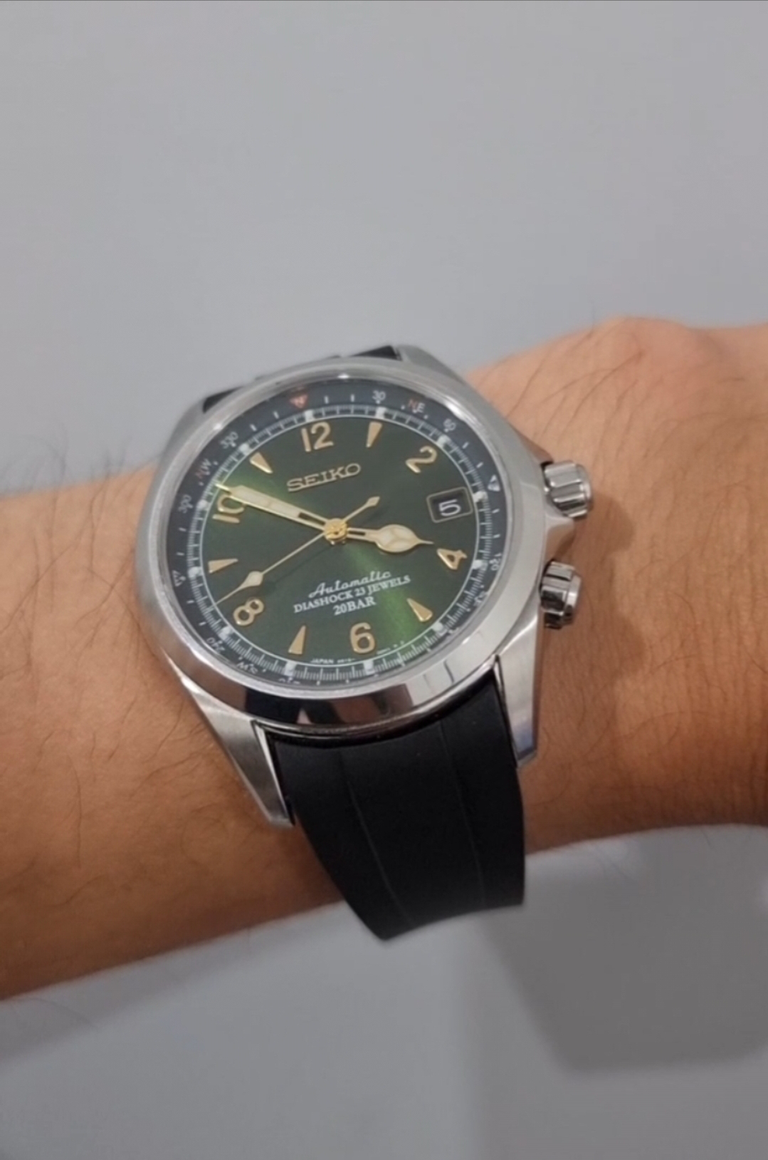 Seiko Alpinist automatic watch with army green dial, stainless steel case, and black rubber strap on wrist