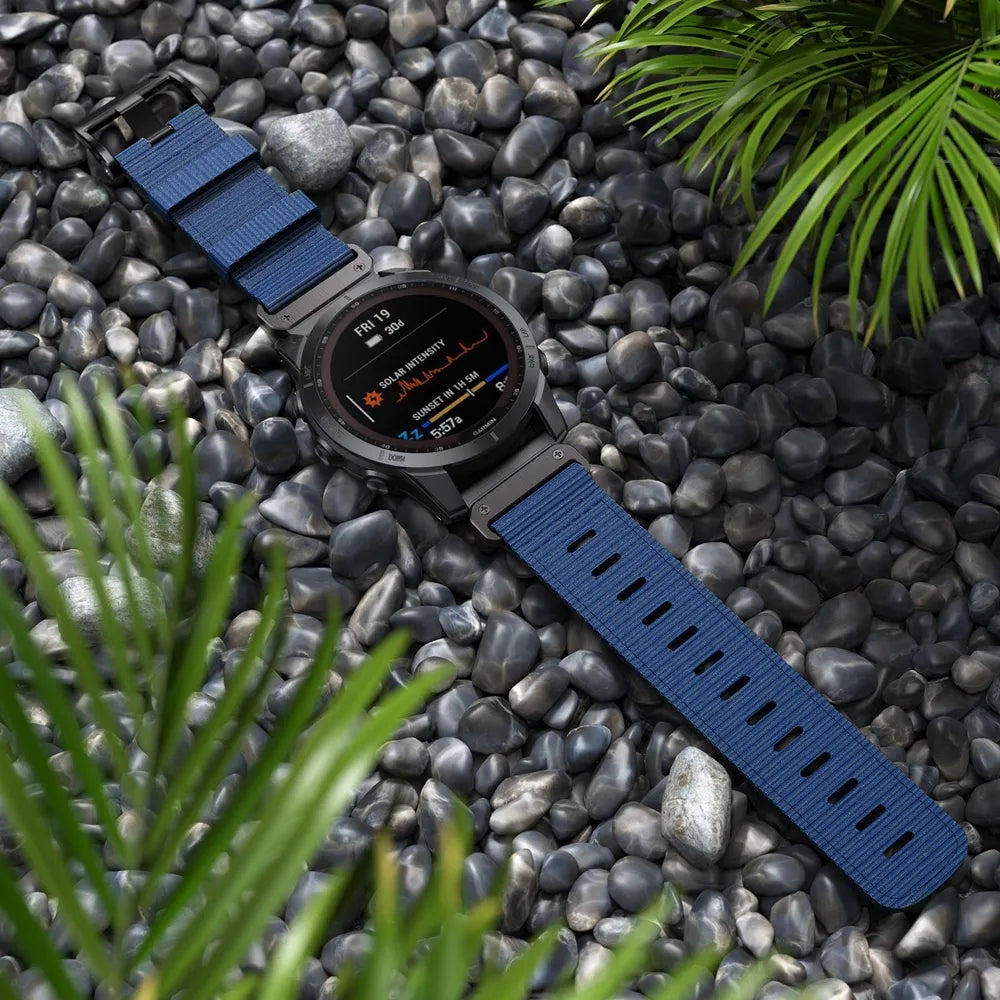 Smartwatch with blue nylon QuickFit army strap on black river rocks surrounded by green plants