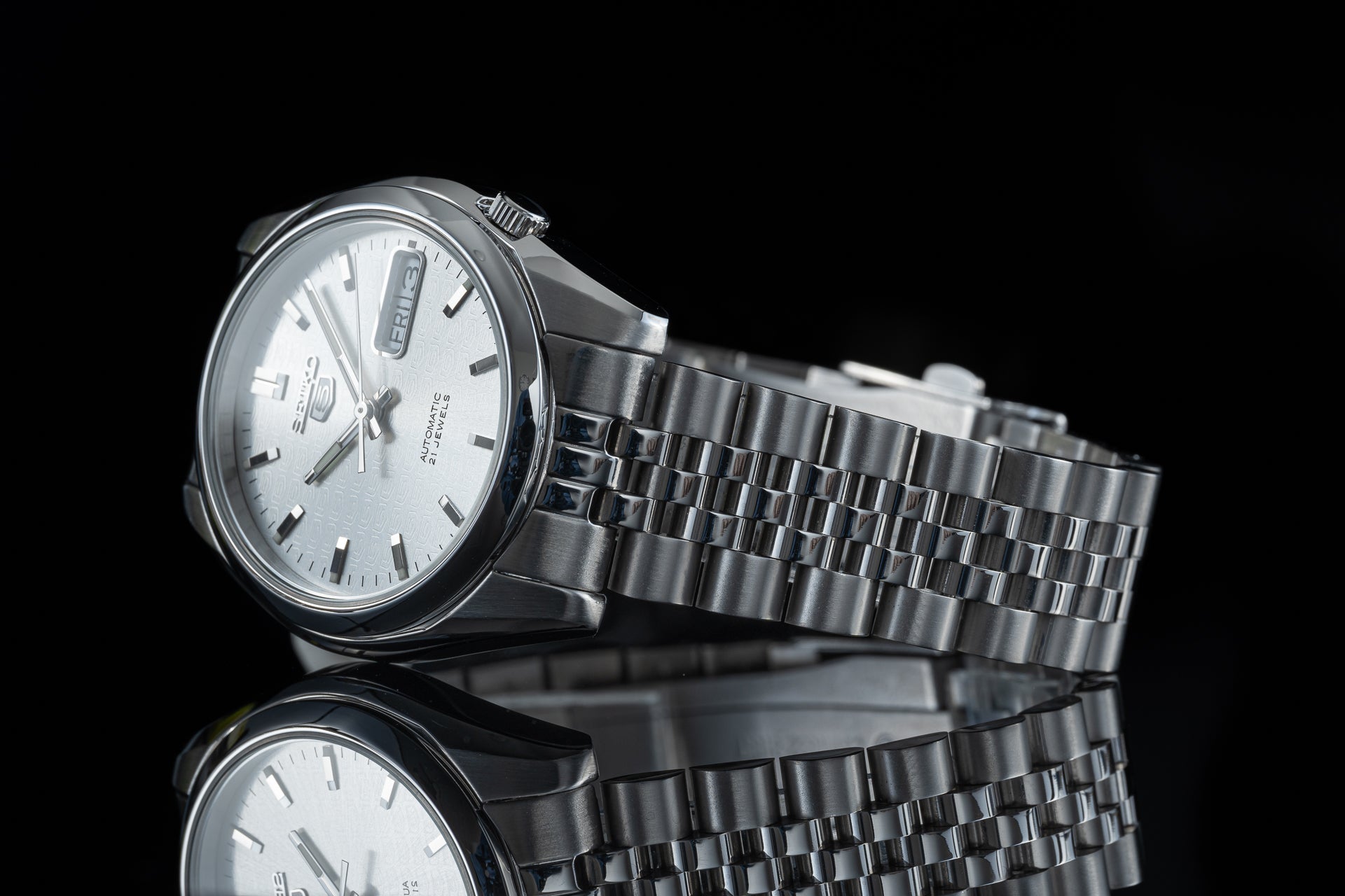 Seiko 5 SNKL stainless steel automatic watch with silver dial and metal bracelet on black background