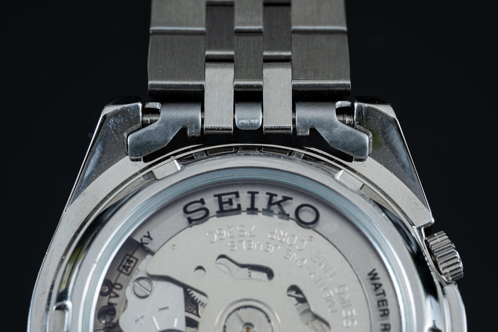 Seiko 5 SNKL stainless steel watch with metal bracelet and exhibition caseback showing automatic movement