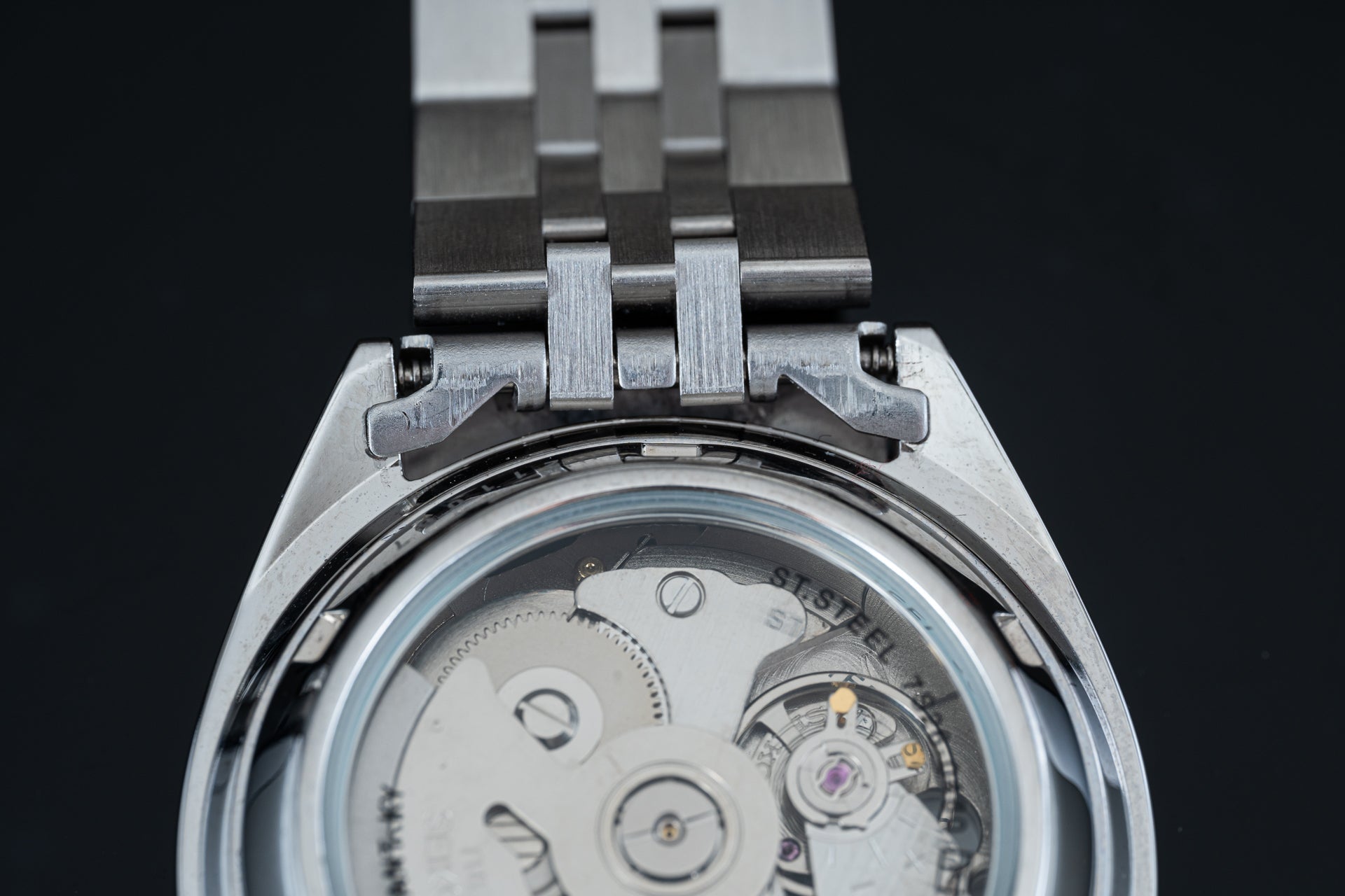 Seiko 5 SNXS stainless steel watch with visible automatic movement through caseback and metal bracelet strap