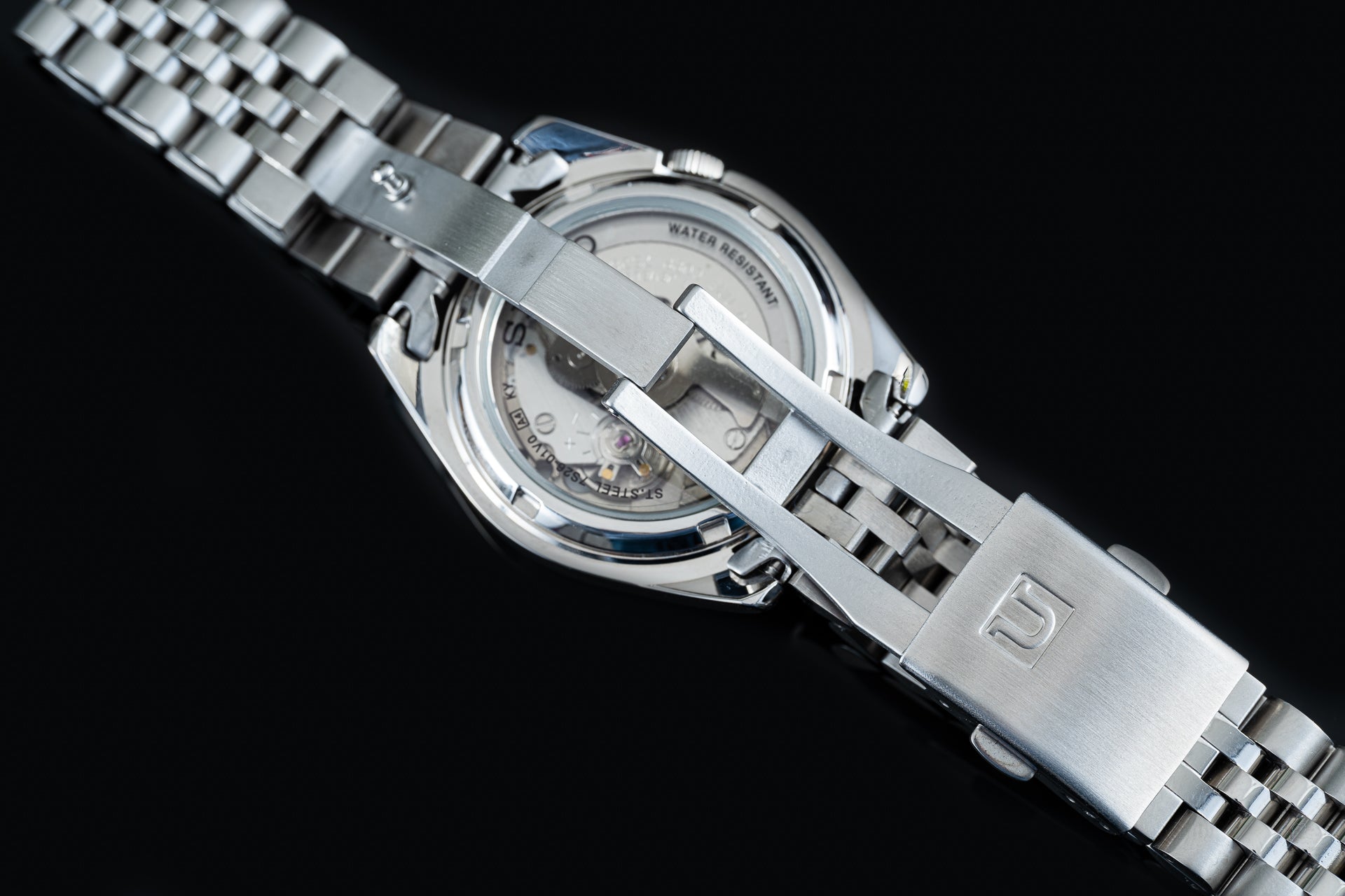 Seiko 5 SNKL stainless steel automatic watch with jubilee bracelet and water resistant case back displayed against black background