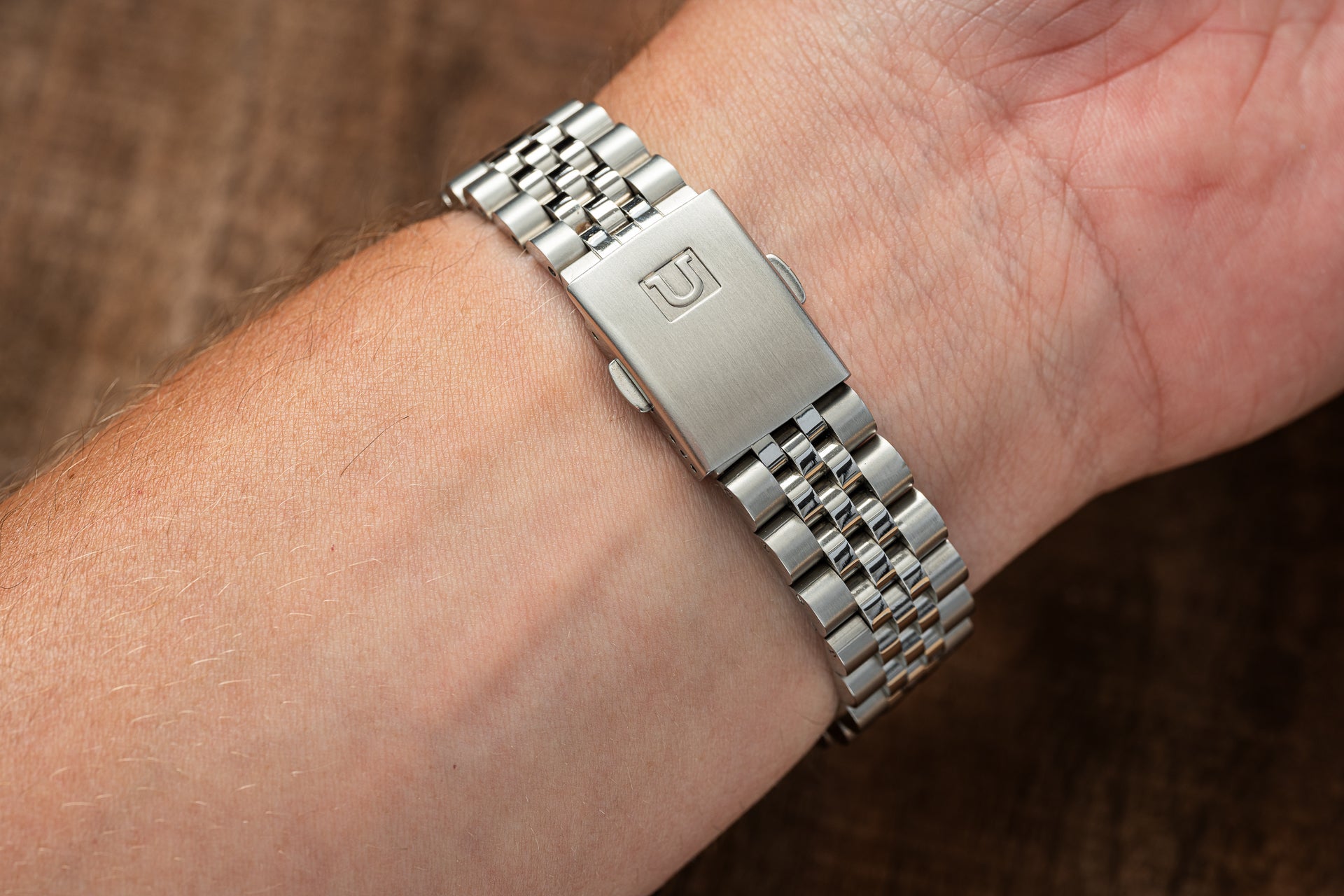 Stainless steel bracelet with jubilee links and branded clasp for Seiko 5 SNXS watch, worn on wrist