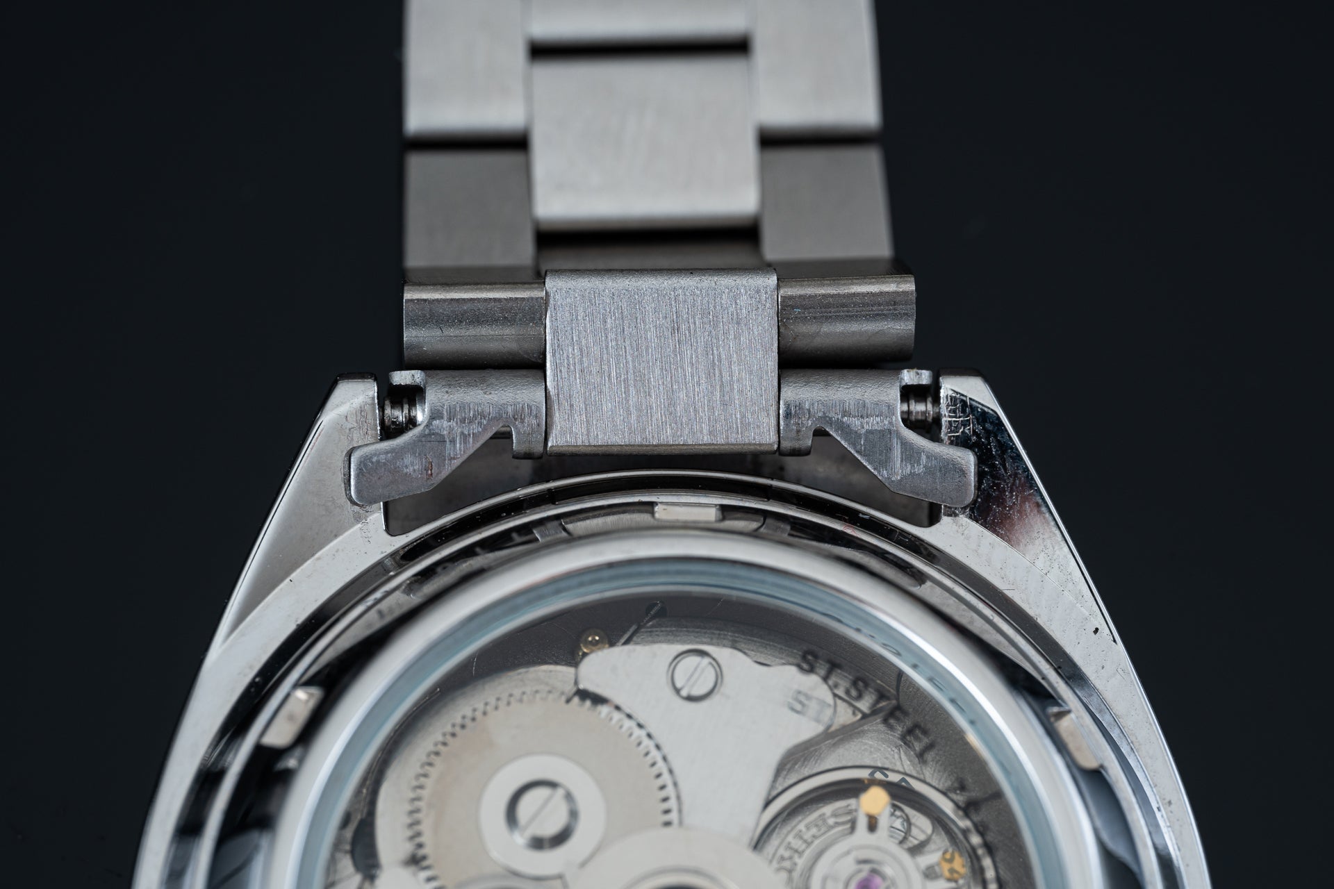 Vintage Seiko 5 SNXS automatic watch with stainless steel bracelet and open caseback displaying mechanical movement