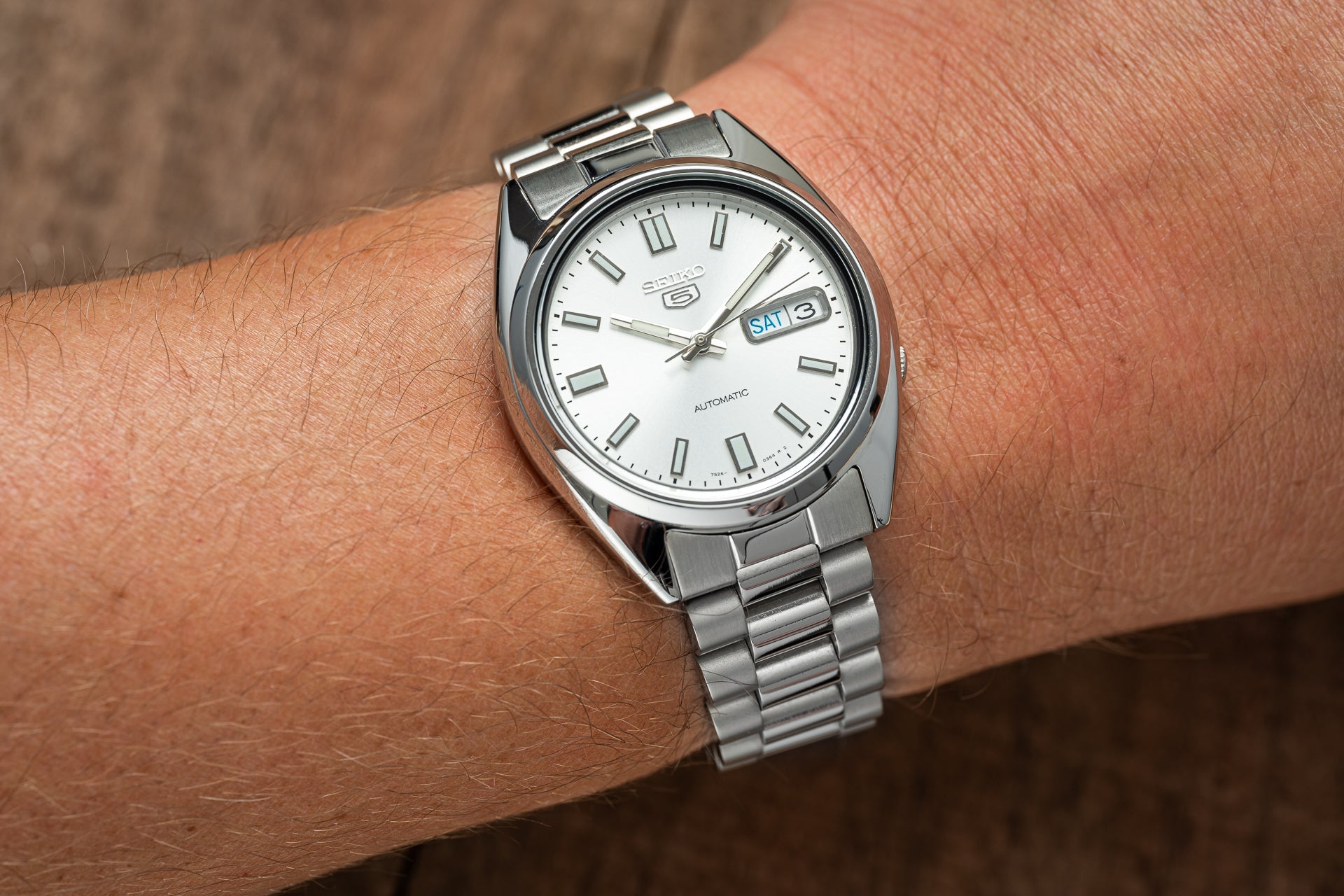Seiko 5 SNXS automatic stainless steel watch with white dial and day-date window on wrist