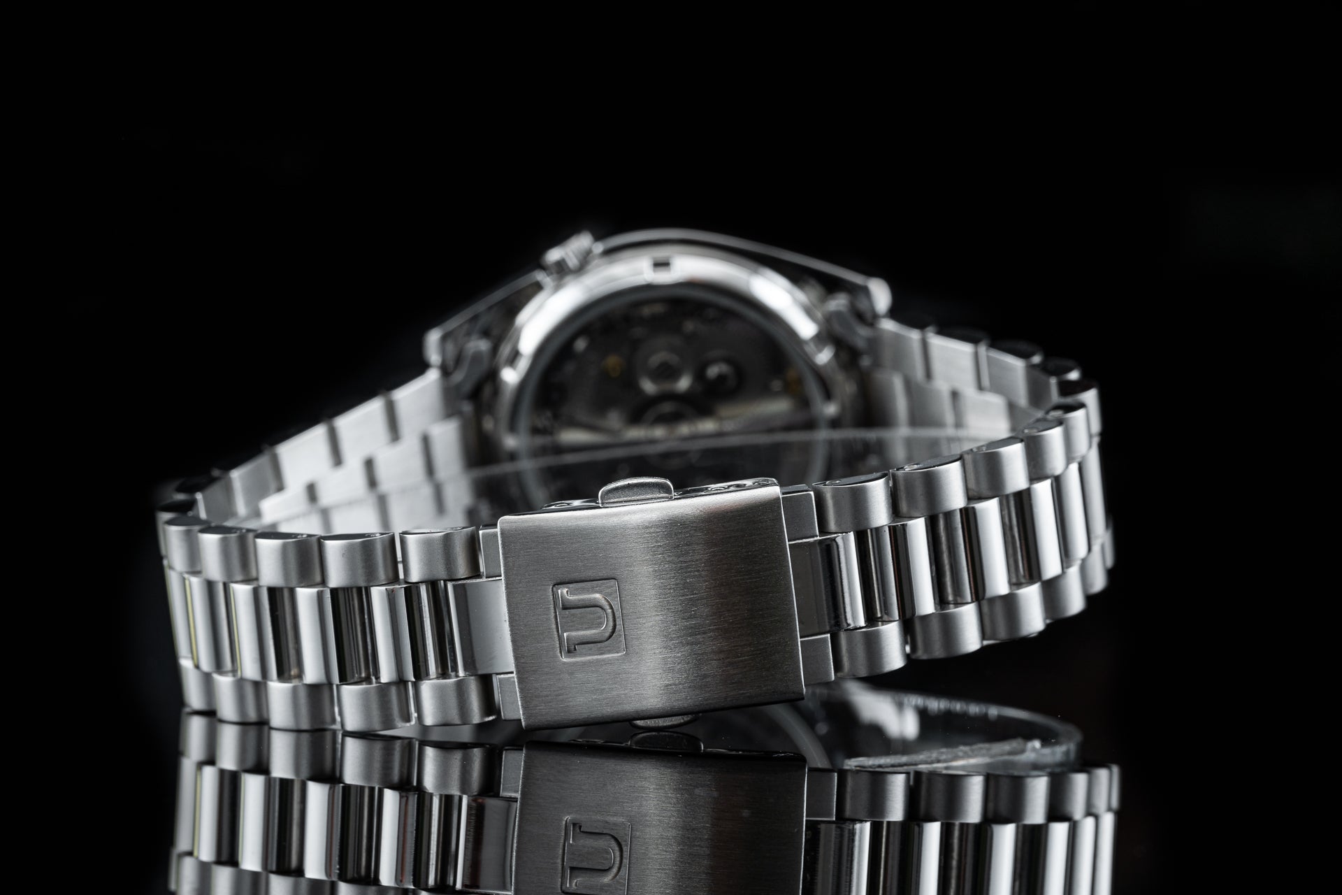 Stainless steel Seiko 5 SNKL watch with brushed metal bracelet and fold-over clasp on black background