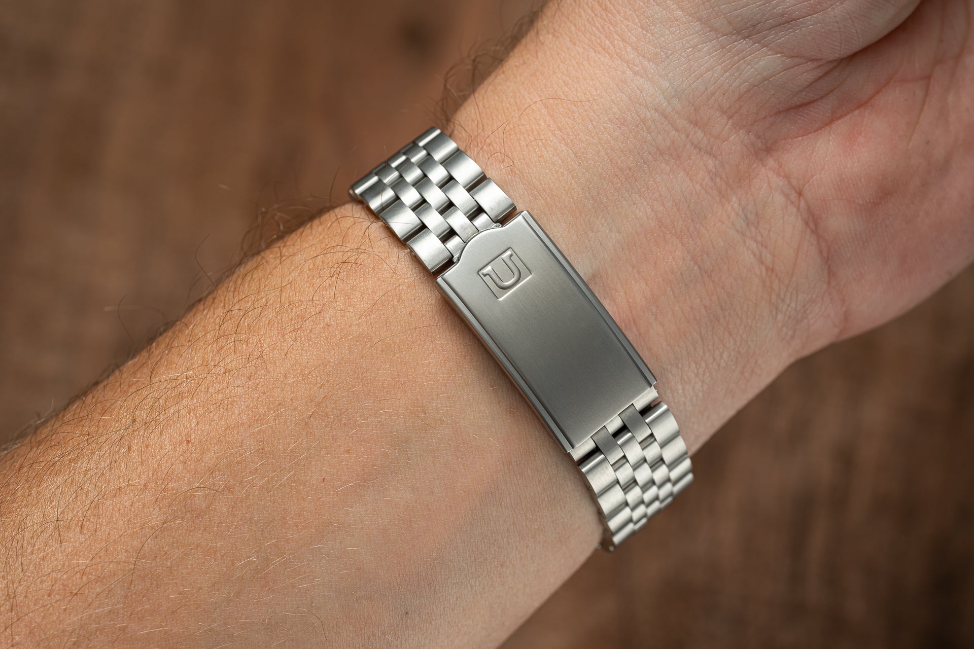 Stainless steel watch bracelet with polished center link and brushed outer links, worn on wrist, compatible with Seiko SNK80x models