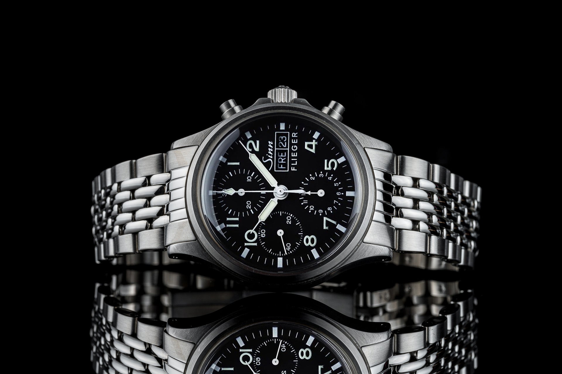 Sinn Flieger 356 chronograph pilot watch with black dial and stainless steel beads of rice bracelet against black background