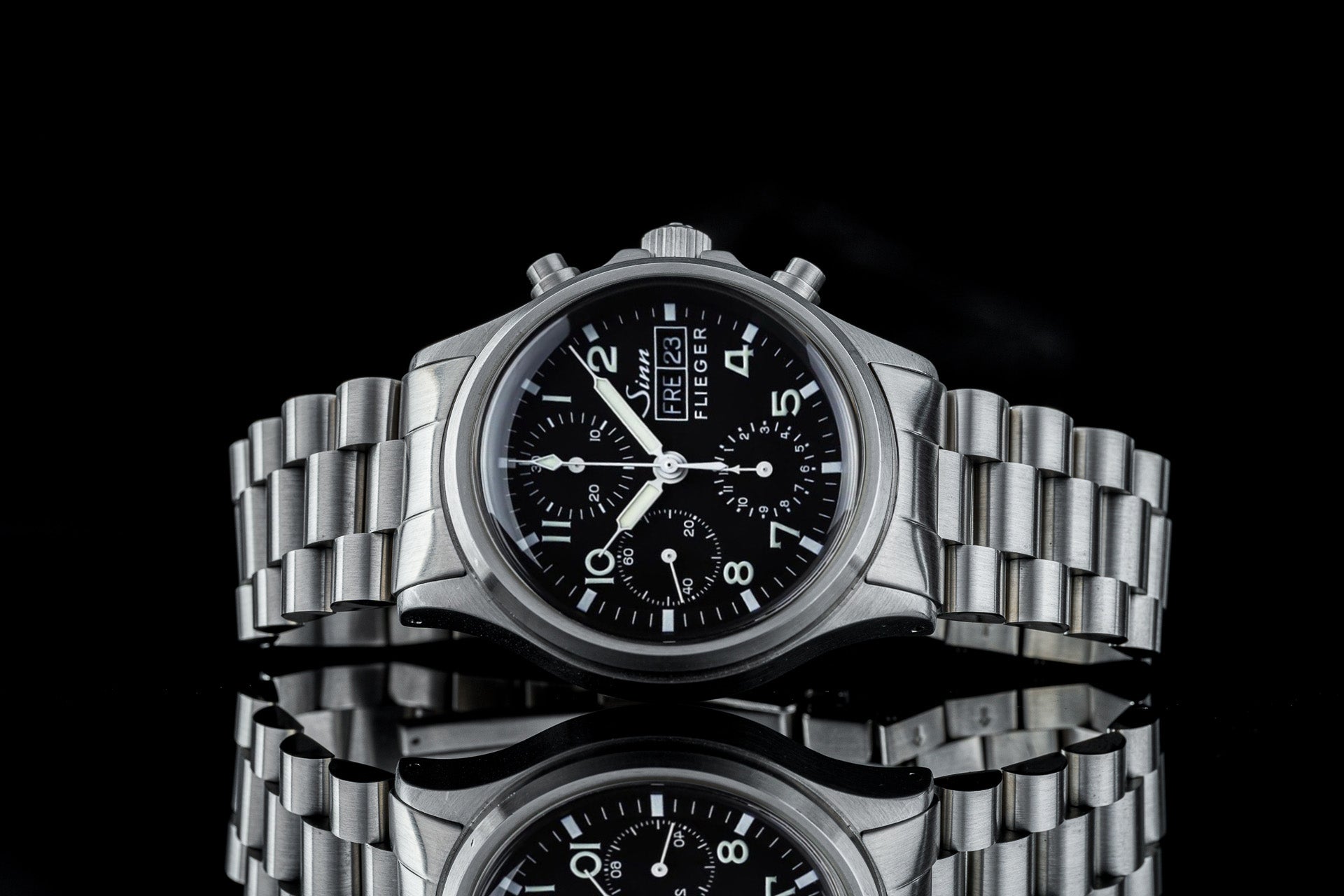 Sinn Flieger 356 stainless steel chronograph watch with black dial and bracelet on reflective black background