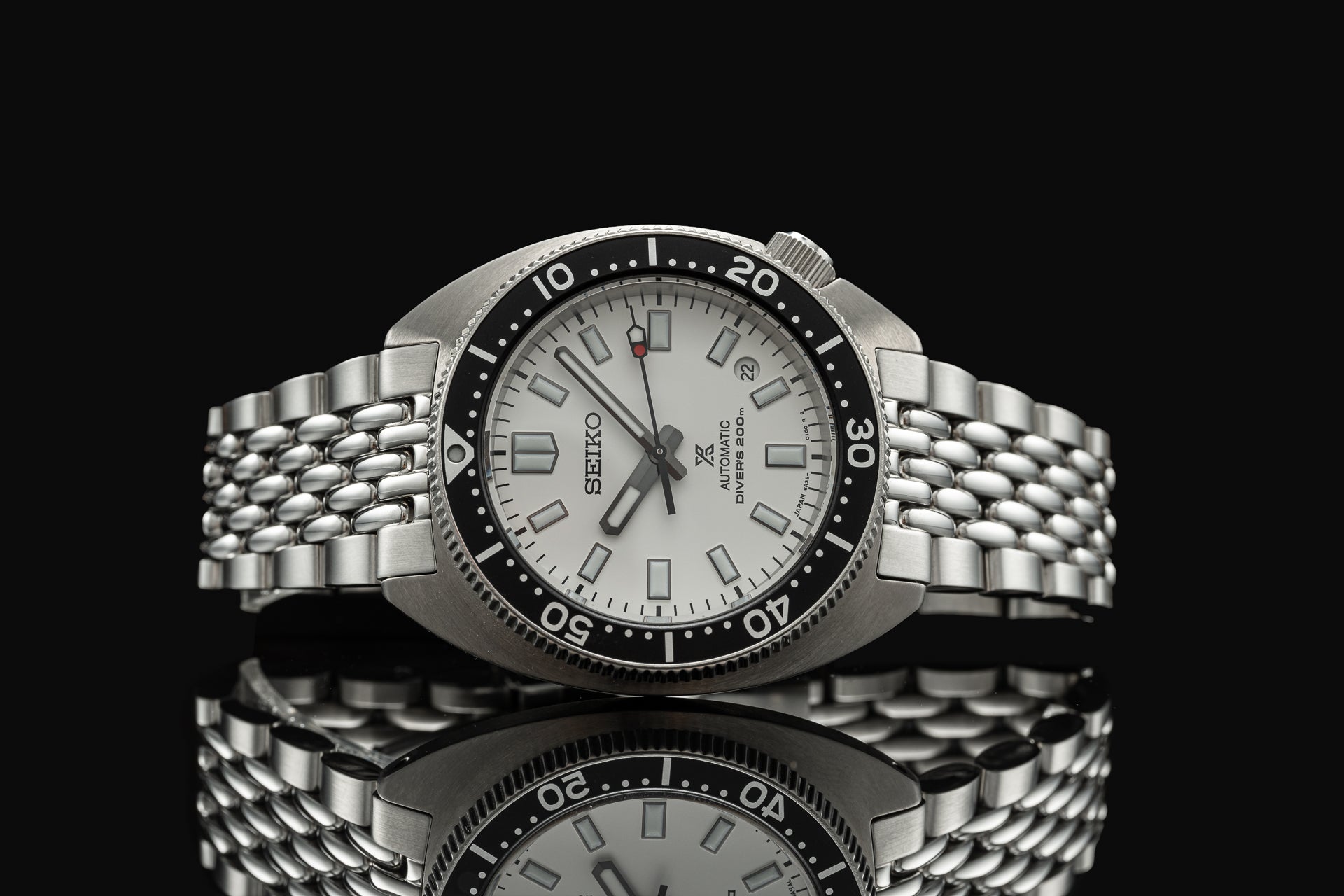Seiko SPB31x Slim Turtle automatic dive watch with silver dial and stainless steel beads of rice bracelet on black background