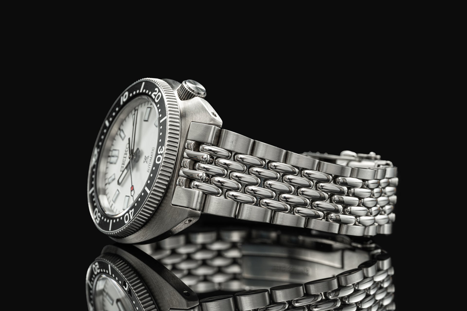 Stainless steel Seiko Slim Turtle dive watch with beads of rice bracelet on black background