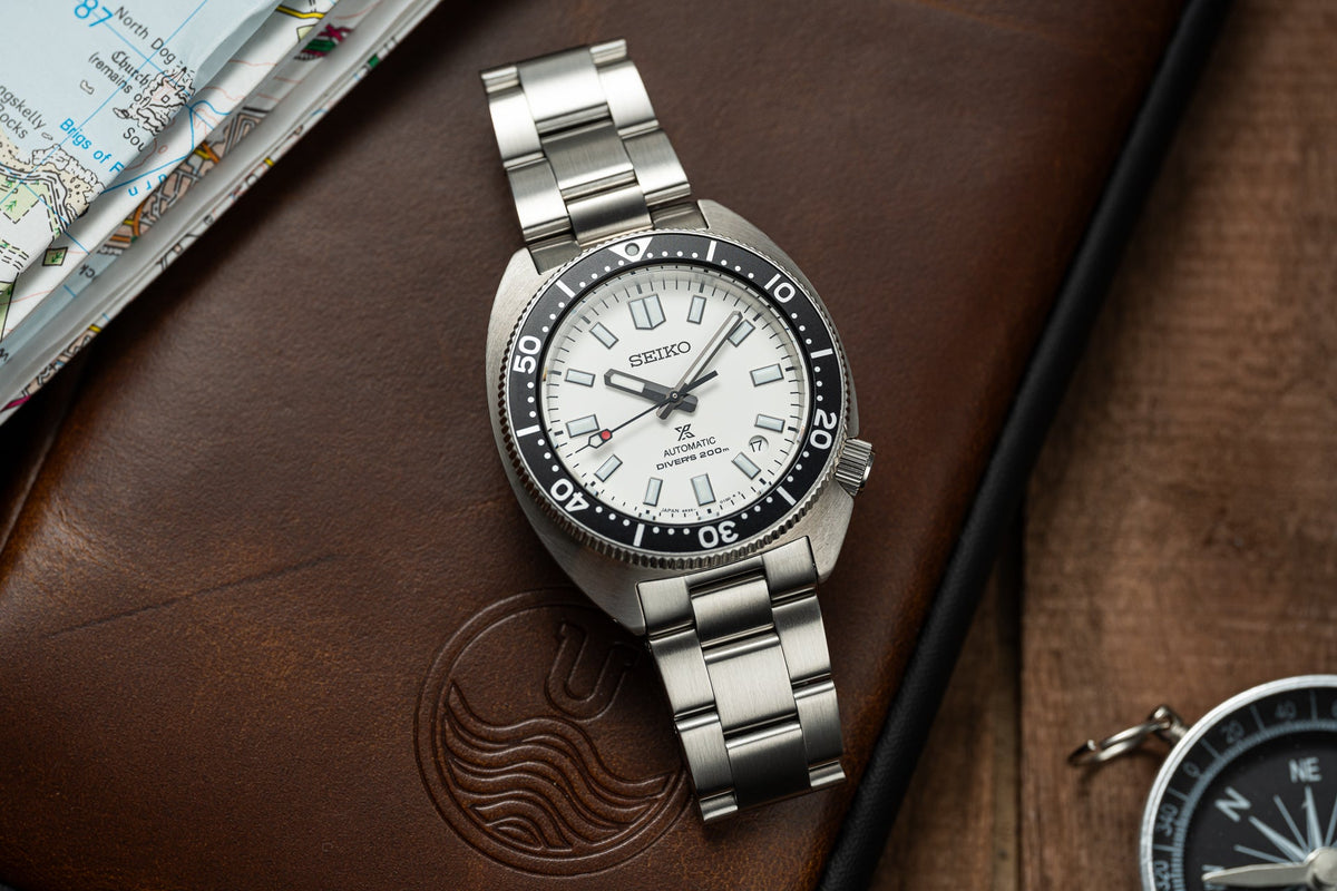 Seiko Prospex Automatic Diver's Watch with stainless steel bracelet, white dial, and black bezel on brown leather desk