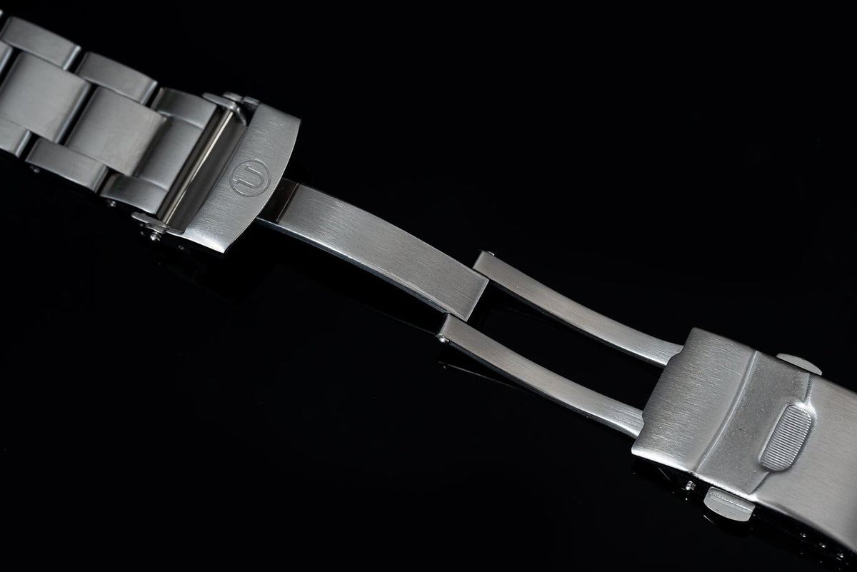 Stainless steel watch bracelet with solid link design for Seiko SPB31x Slim Turtle, featuring brushed finish and fold-over clasp on black background
