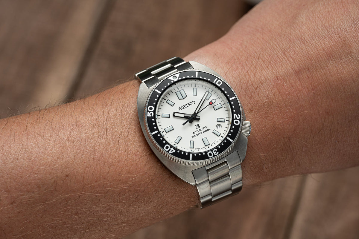 Seiko automatic diver watch with white dial, black bezel, and stainless steel bracelet worn on wrist