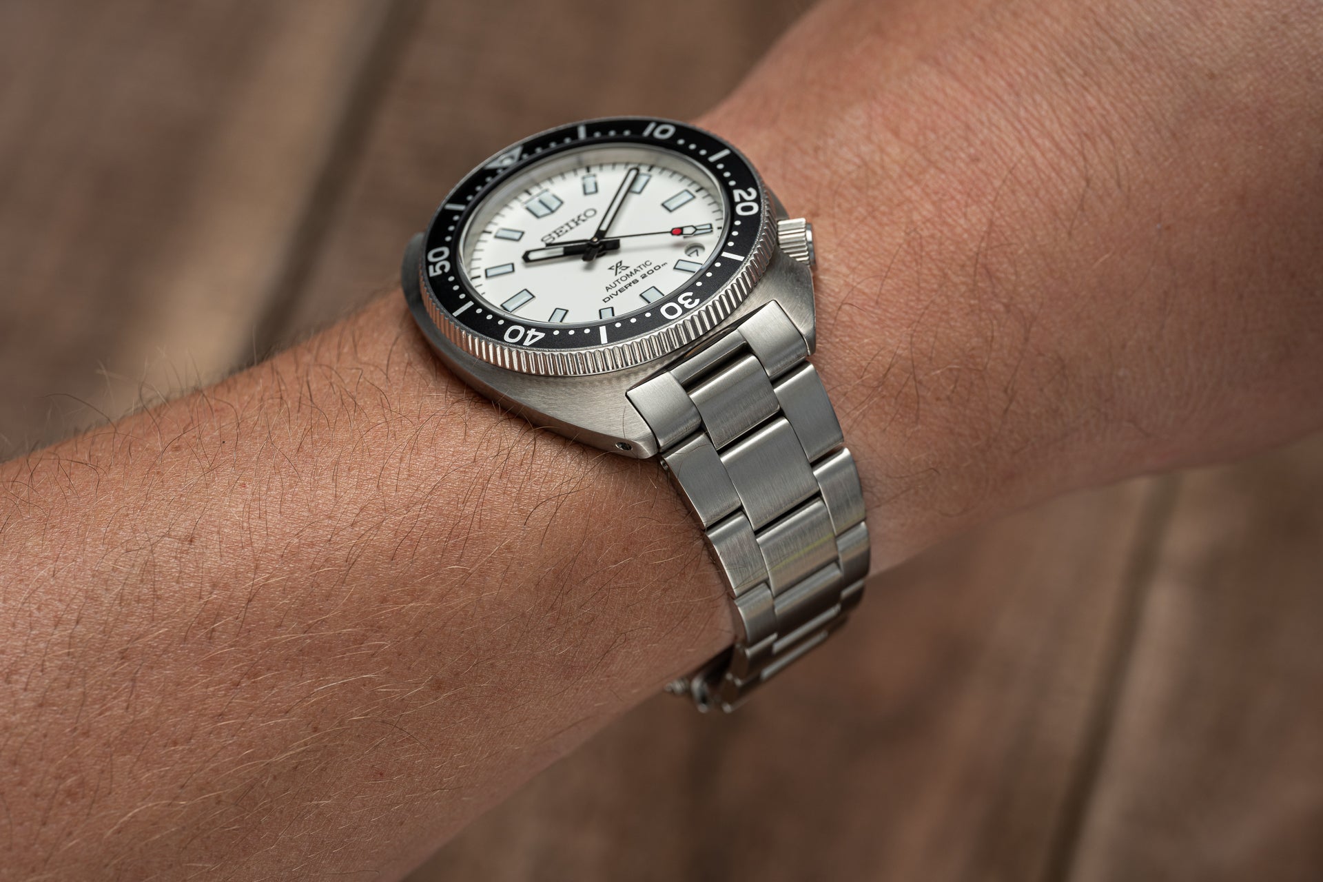 Seiko automatic dive watch with white dial, black bezel, and stainless steel bracelet worn on wrist