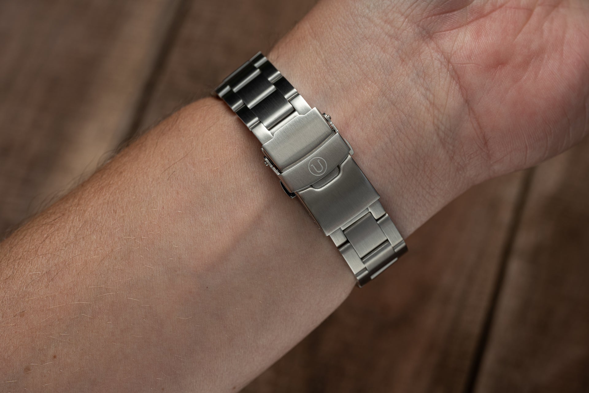 Two-tone stainless steel watch bracelet with mixed metal links worn on wrist, featuring brushed and polished finish