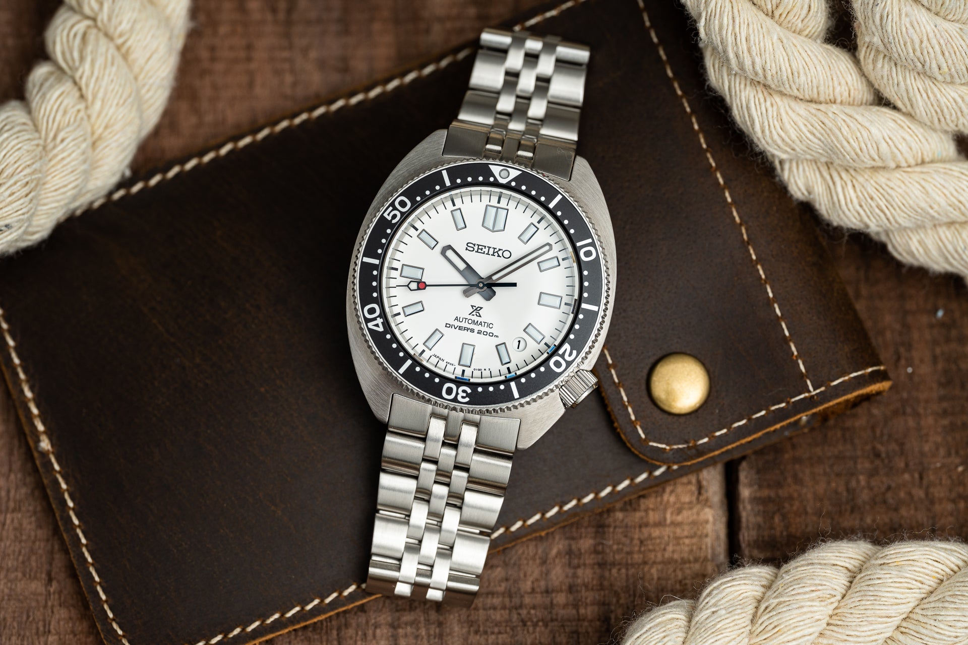 Seiko SPB31x automatic dive watch with white dial, black bezel, stainless steel jubilee bracelet on brown leather background