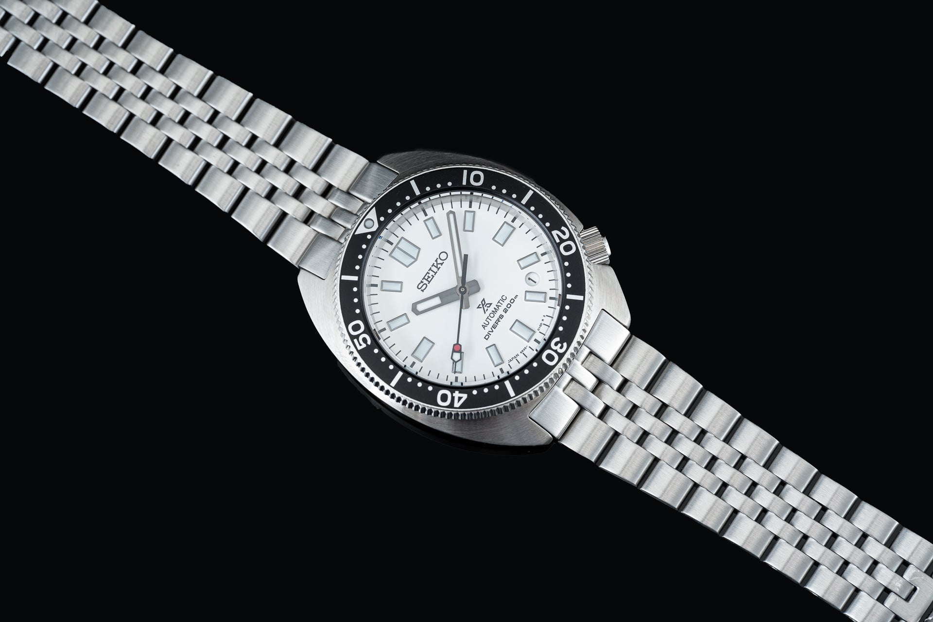 Seiko SPB31x Slim Turtle automatic dive watch with white dial, black bezel, and stainless steel bracelet on black background