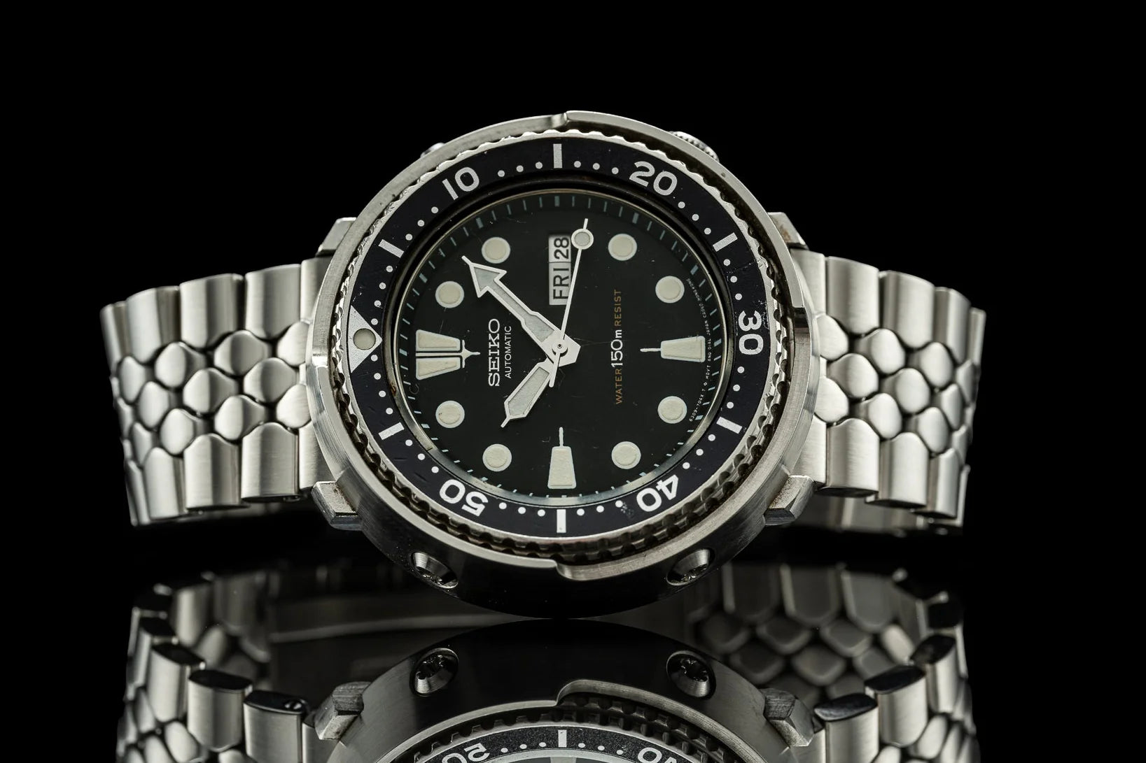 Seiko automatic diver watch with black dial, rotating bezel, luminous hands, steel bracelet on black background