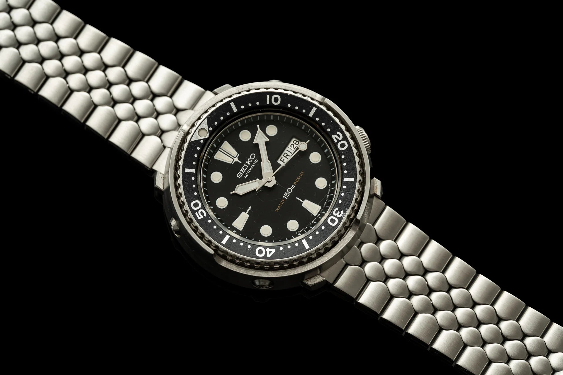 Seiko dive watch with black dial, stainless steel bracelet and bezel on black background