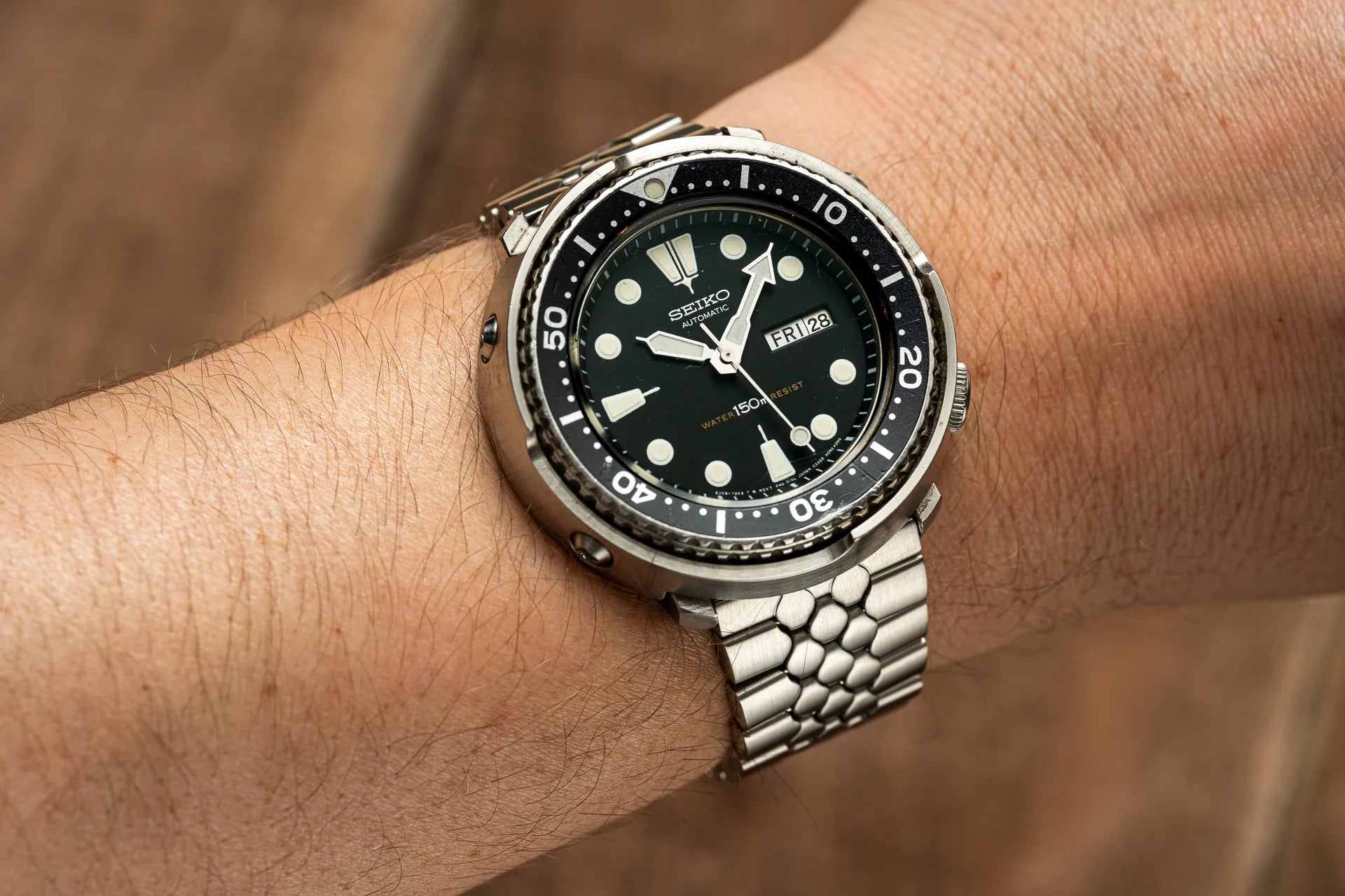 Seiko automatic dive watch with black dial, white indices, date window, stainless steel bracelet on wrist