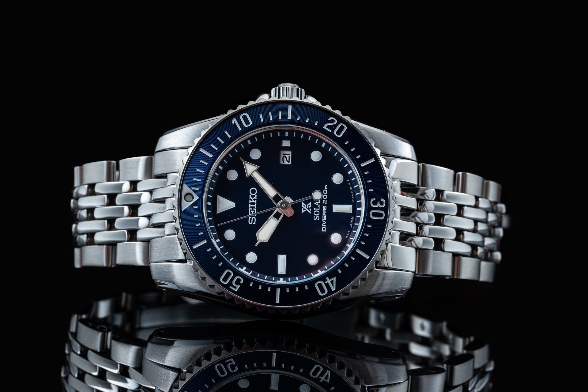 Seiko Solar diver watch with stainless steel beads of rice bracelet, black dial and rotating bezel on black background