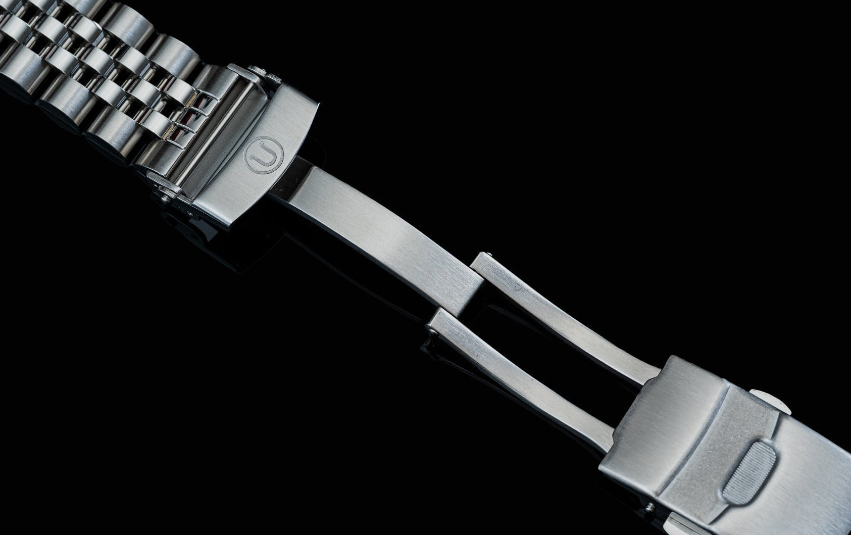 Stainless steel solar watch bracelet with metal links and clasp against black background