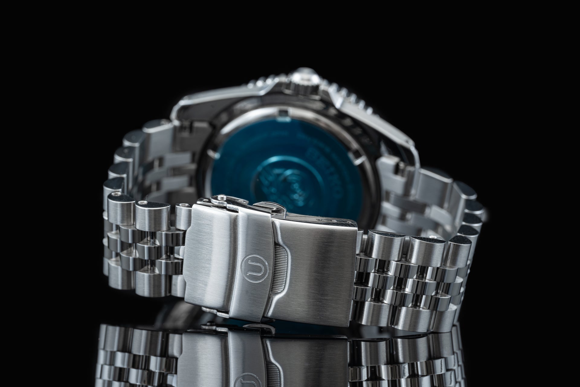 Stainless steel solar watch with blue dial and matching metal bracelet, featuring fold-over safety clasp on black background