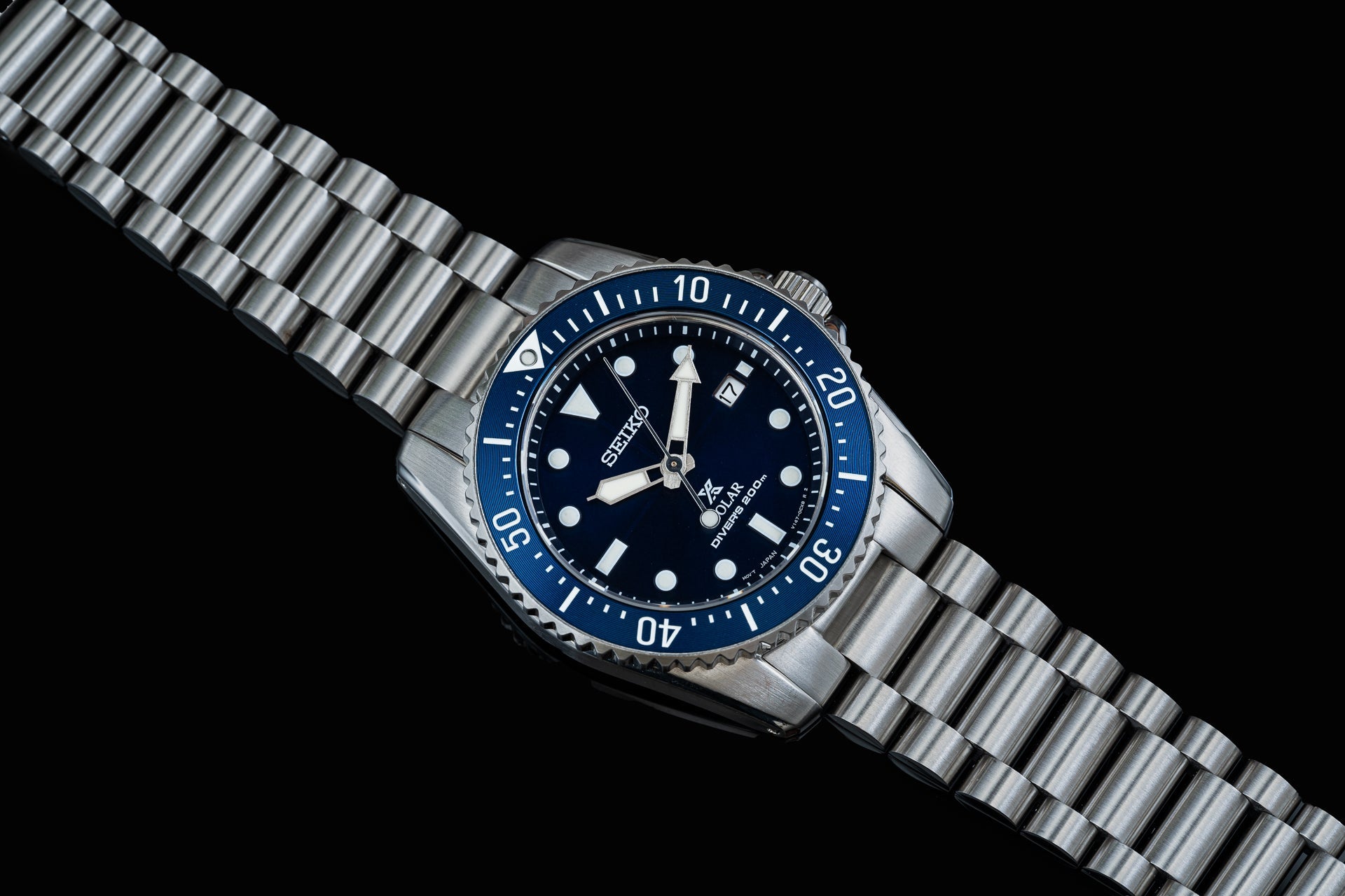 Seiko solar dive watch with dark blue dial, white indices, stainless steel bracelet and rotating bezel on black background