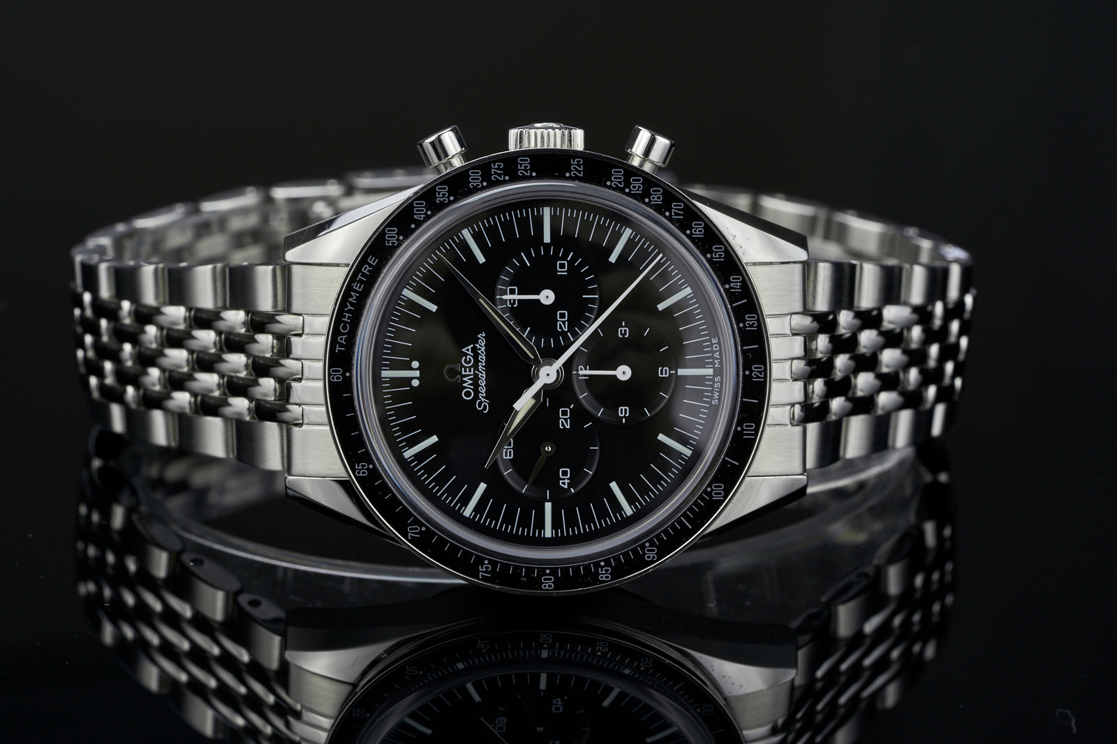 Omega Speedmaster chronograph watch with black dial, tachymeter bezel, steel Beads of Rice bracelet on dark background
