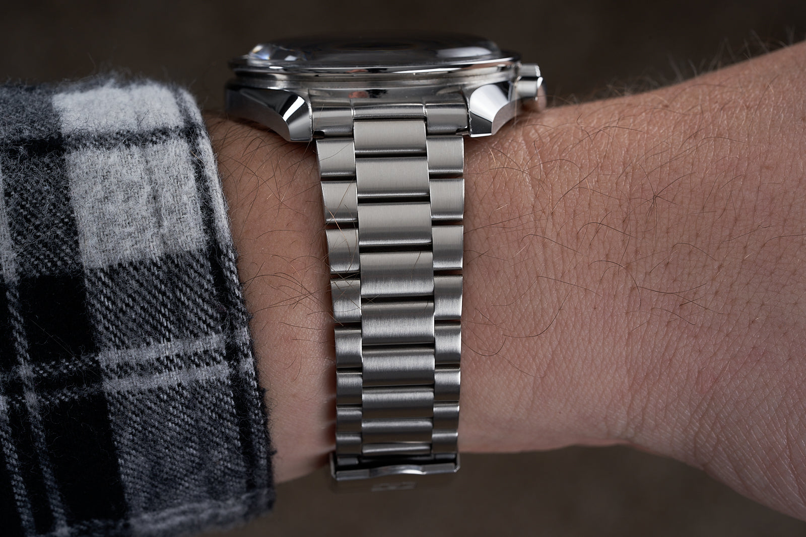 Stainless steel bracelet for Omega Speedmaster with 19/20mm lugs worn on wrist with plaid sleeve