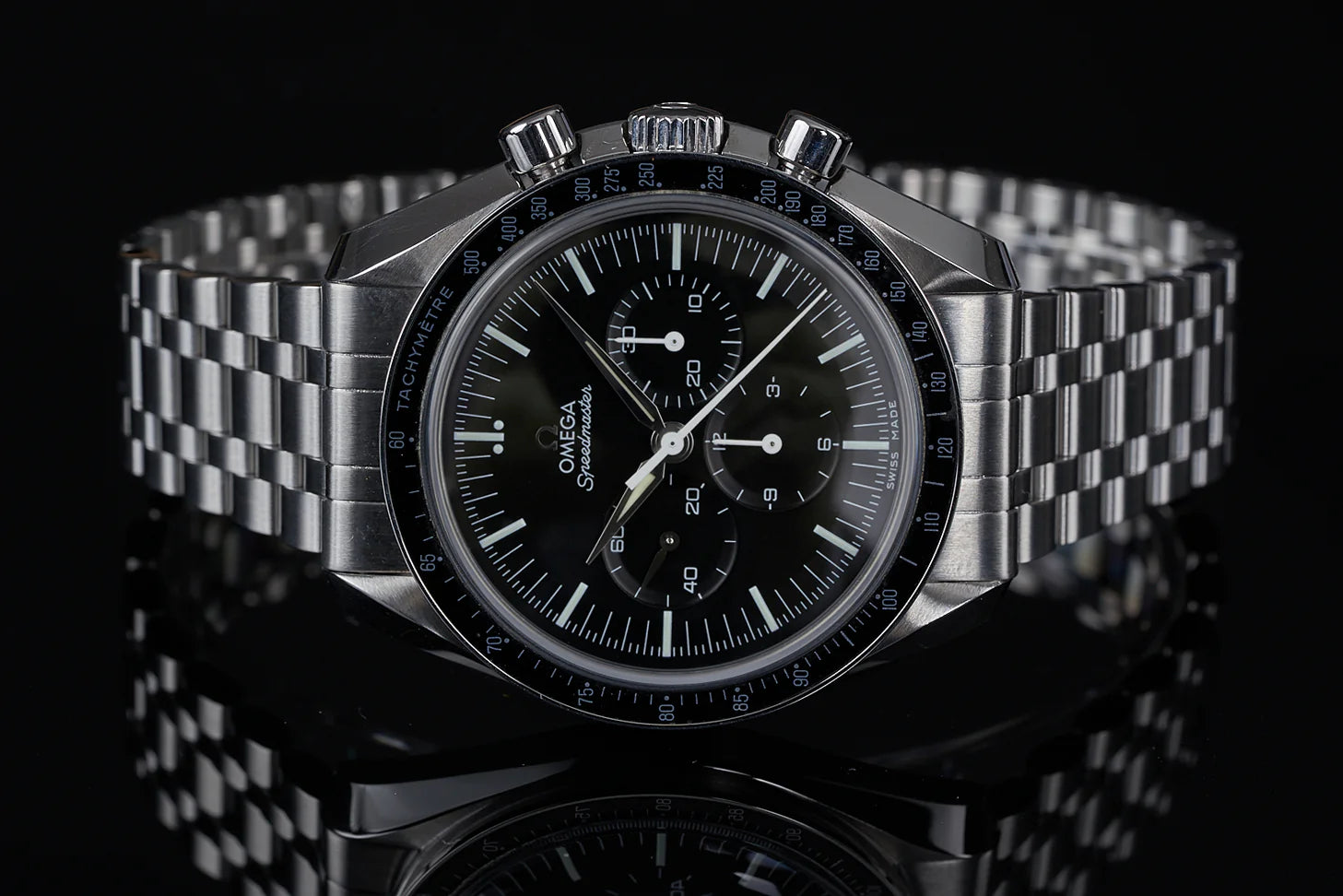 Omega Speedmaster Professional chronograph watch with steel bracelet, black dial, tachymeter bezel, and three subdials on dark background